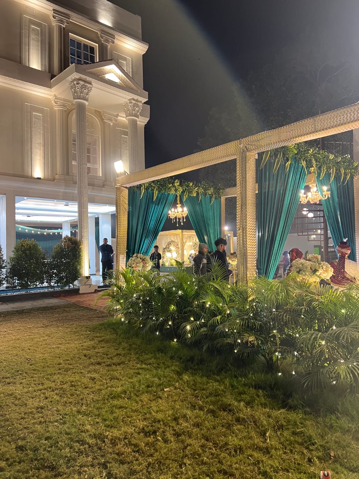Garden pergola and mandap with teal drapes in the evening light