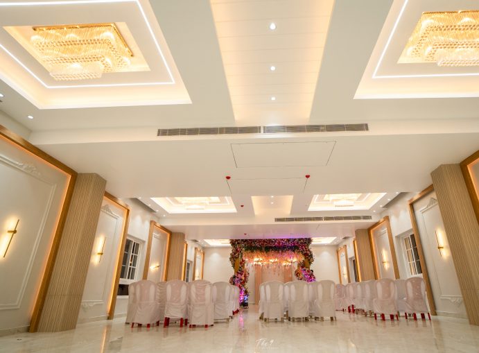 Air-conditioned banquet hall with crystal chandeliers, stage and draped chairs